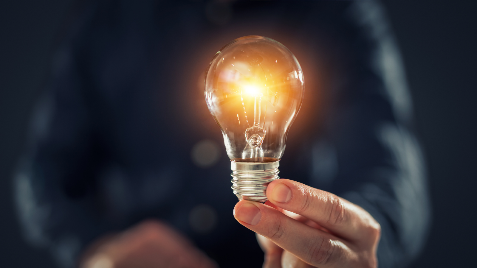 Man holding a lit up lightbulb indicating new ideas for leading sales teams.