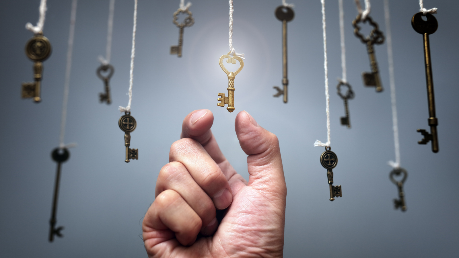 Man holding up a highlighted key in a ceiling full of various keys.