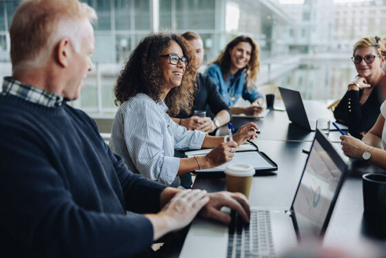Team of six people in a conference room discussing business partners