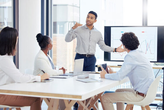 man presenting data to three individuals around table