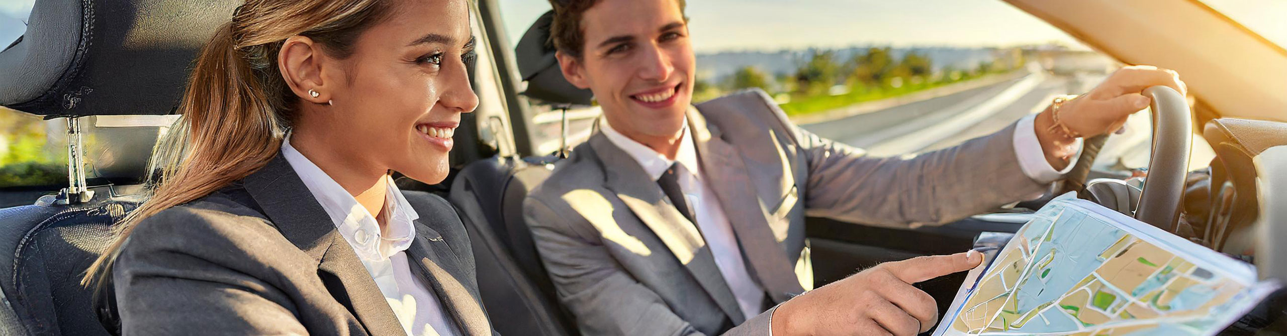 Male and female sales rep navigating map in car