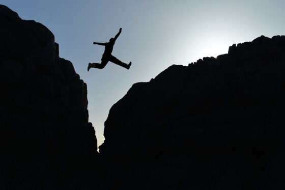 Silhouette jumping rocky gap