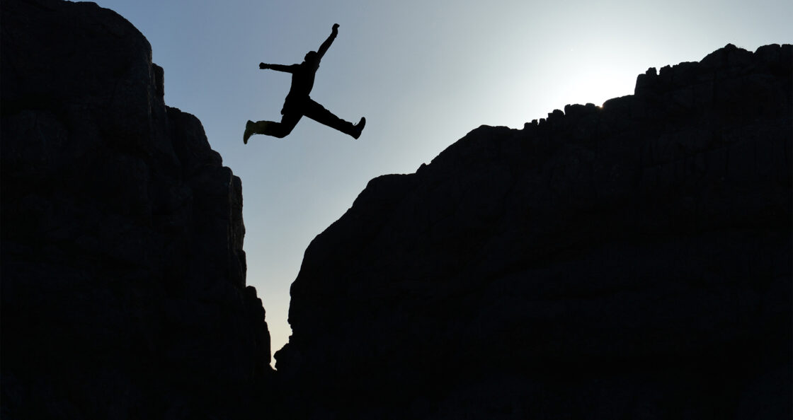 Silhouette jumping rocky gap