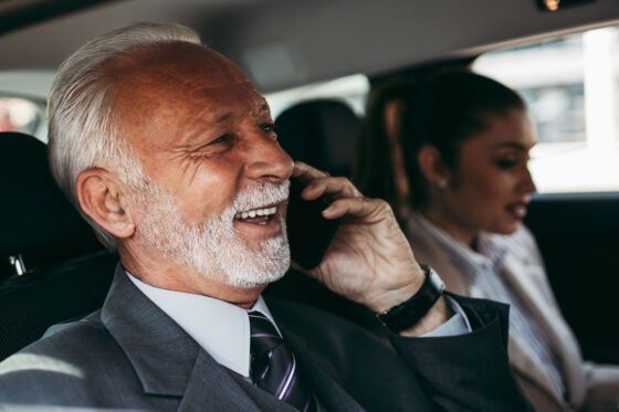 Senior manager sitting in car on phone with field sales rep in passenger seat