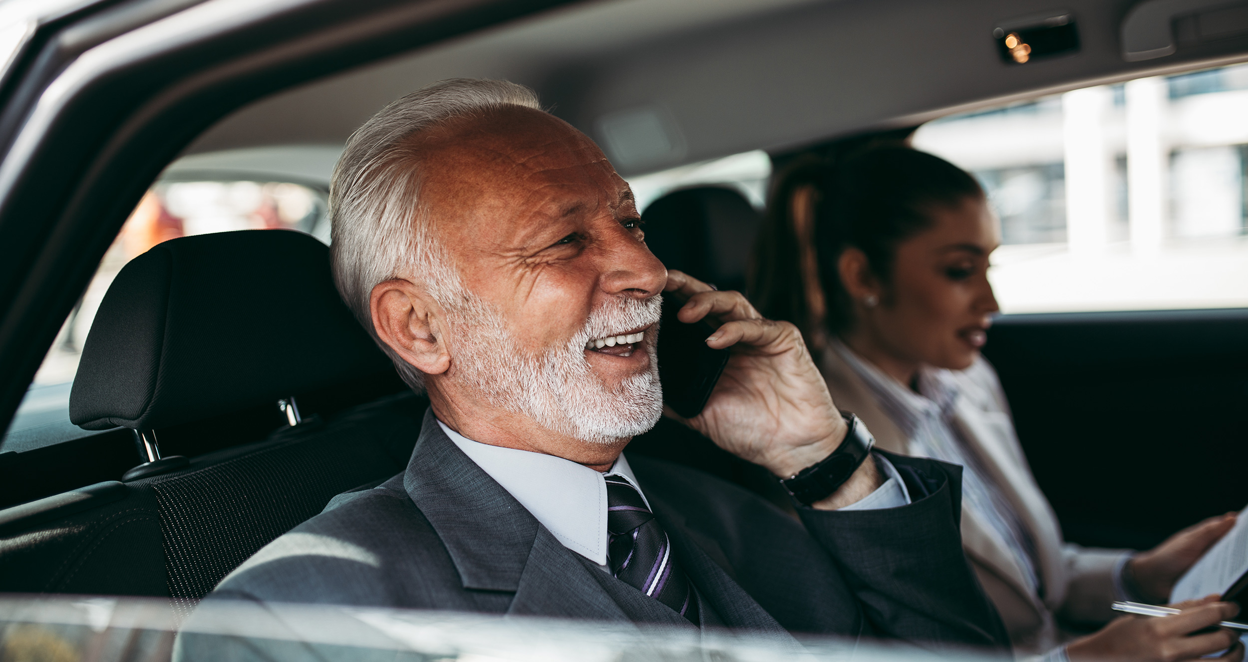 Senior manager sitting in car on phone with field sales rep in passenger seat