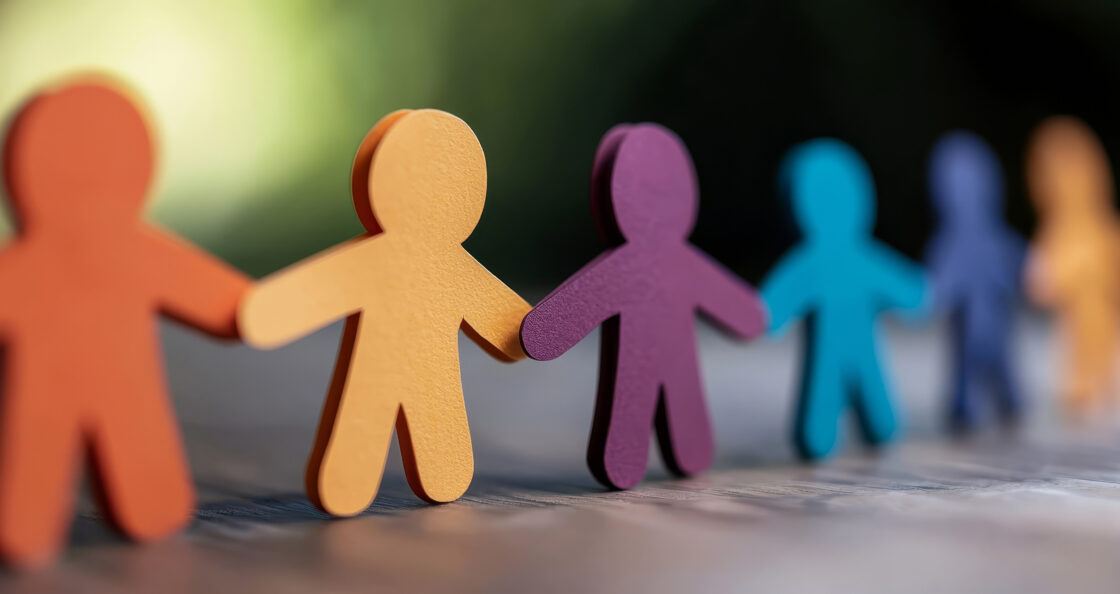 Colorful paper cutout figures holding hands in a row, symbolizing diversity, unity, and teamwork. 