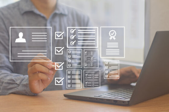 individual sitting on laptop reviewing checklists and documents for product launch
